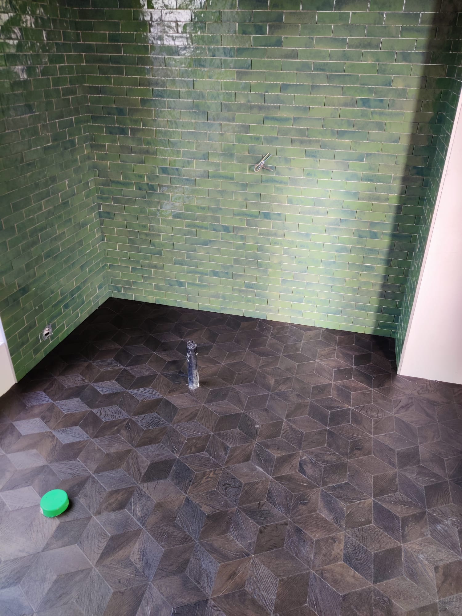 Antraciet PVC vloer met cube-motief in een badkamer met groene wandtegels