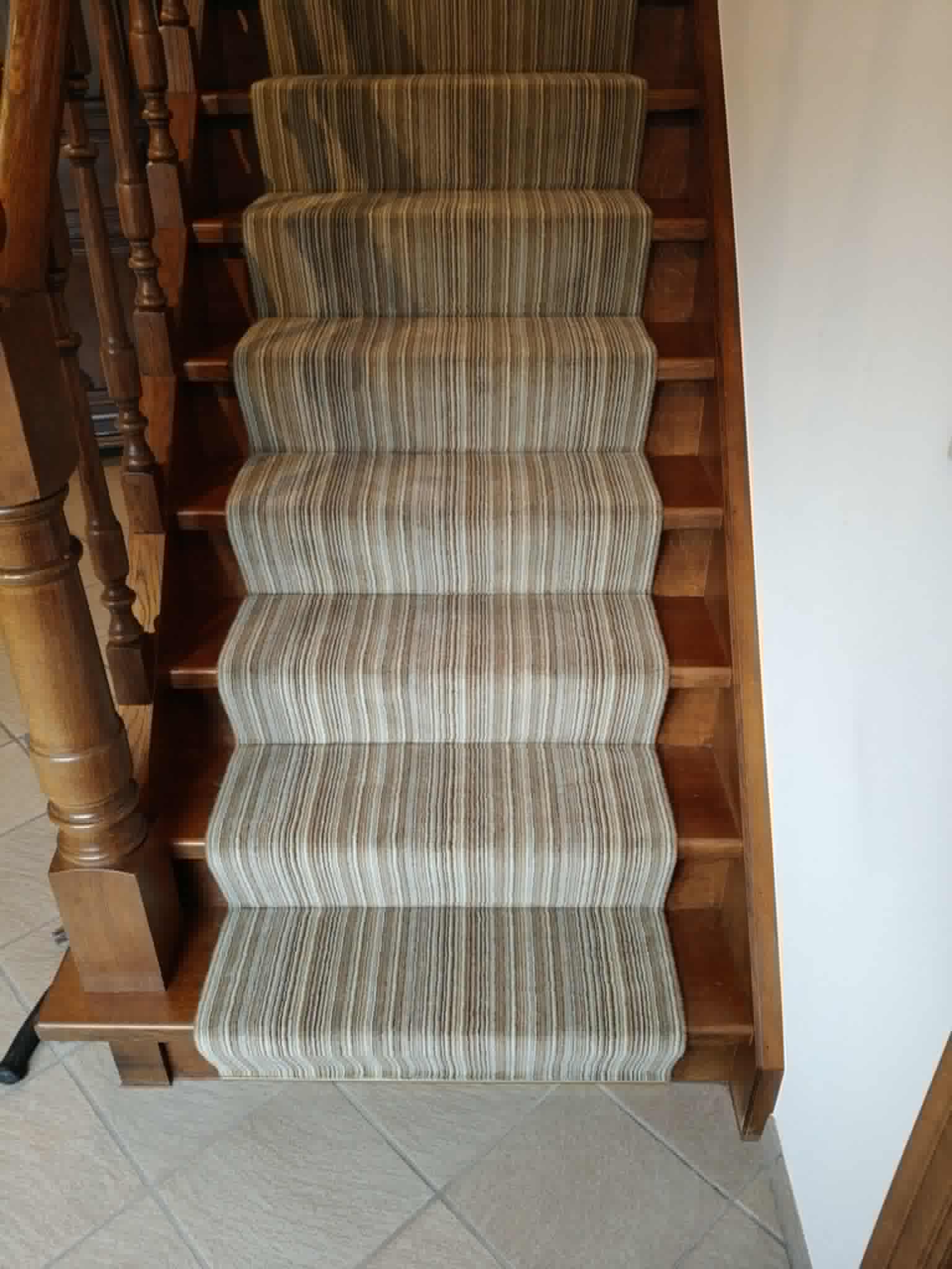 Gestreepte tapijtloper op een houten trap met klassiek leuningwerk